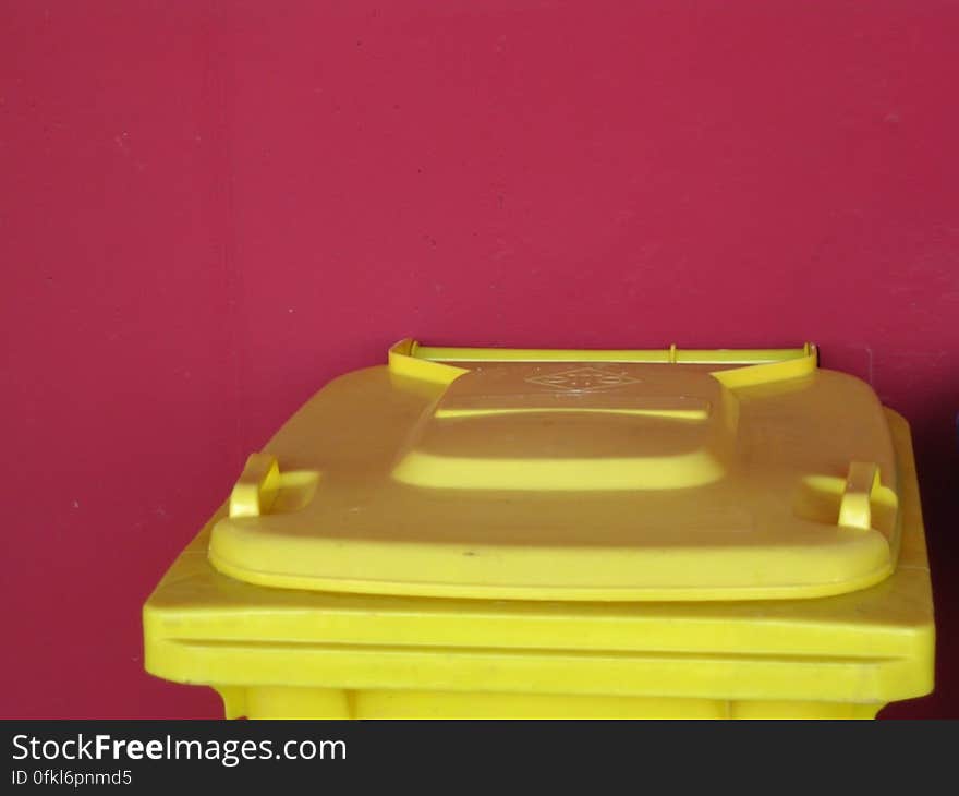 yellow-trash-bin-against-red-wall