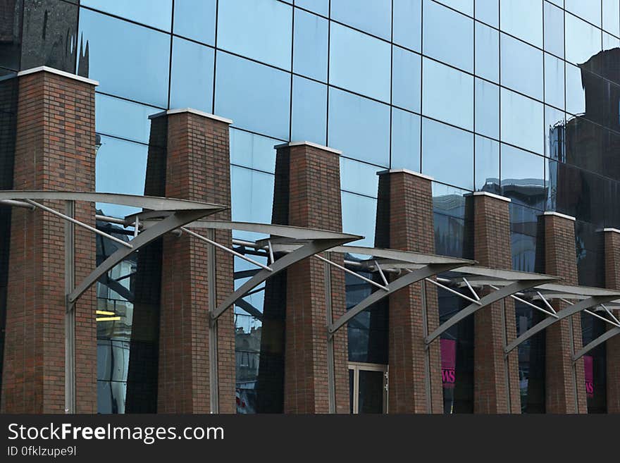 Glass and steel facade of a modern hotel, reflecting old city elements.