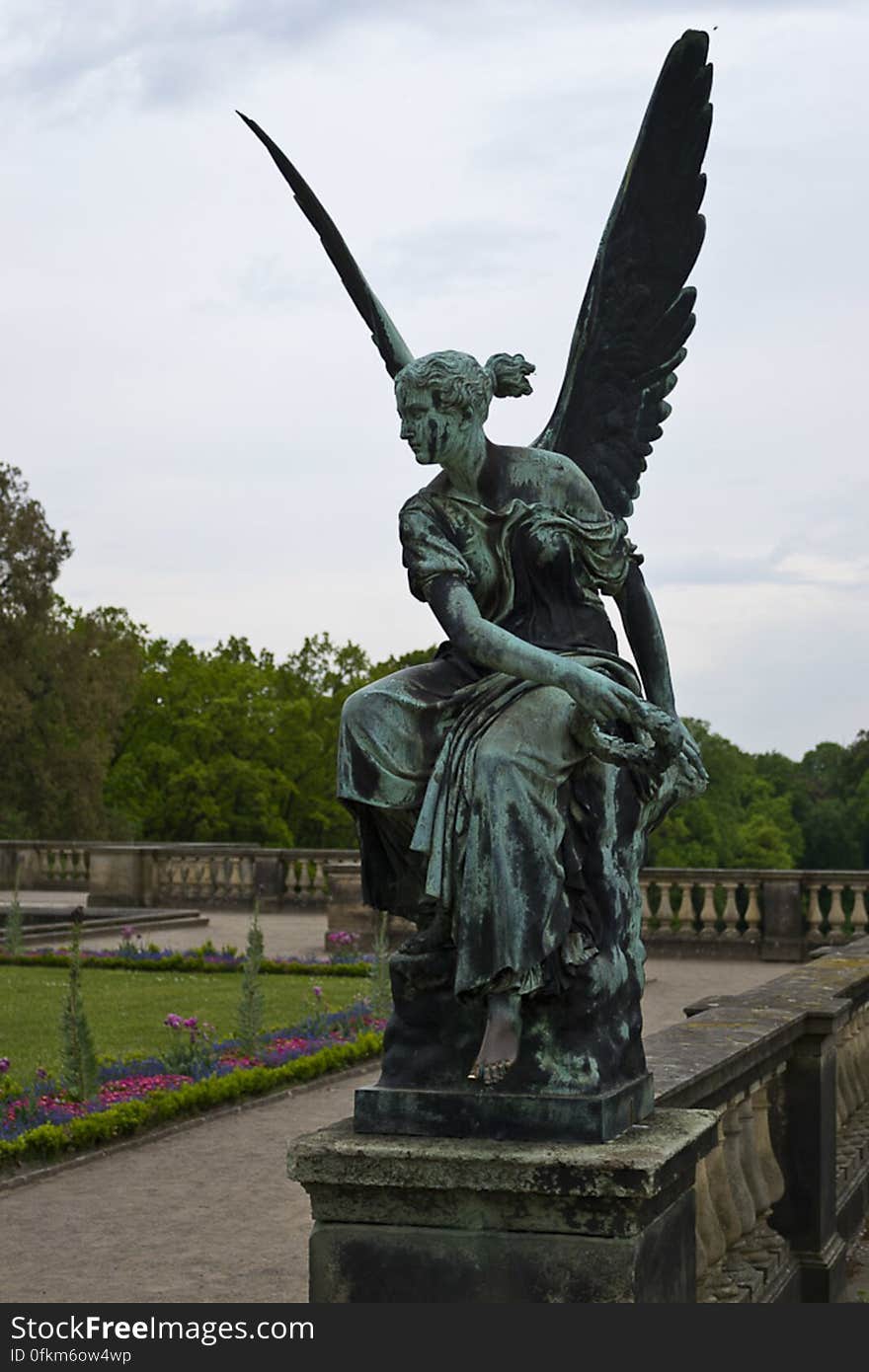 Sculpture of a winged angel holding a wreath in front of Orangerie in Potsdam. Visitors like to rub the statue&#039;s bare left foot. Sculpture of a winged angel holding a wreath in front of Orangerie in Potsdam. Visitors like to rub the statue&#039;s bare left foot.