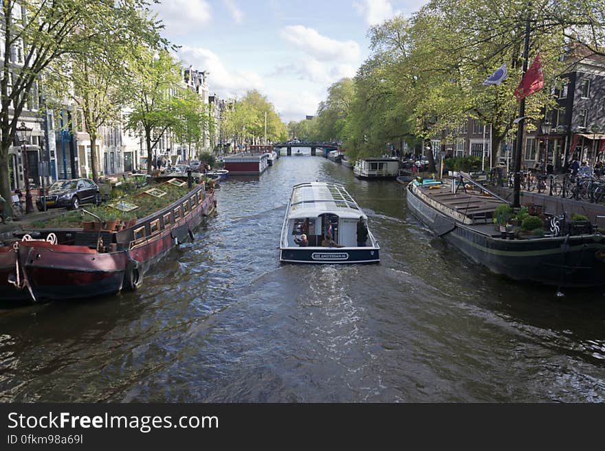 Prisengracht canal is the longest of the three main canals of Amsterdam. Here a tourist cruise boat passes along the Musem Boat &#x28;Hendrika Maria freighter&#x29;.