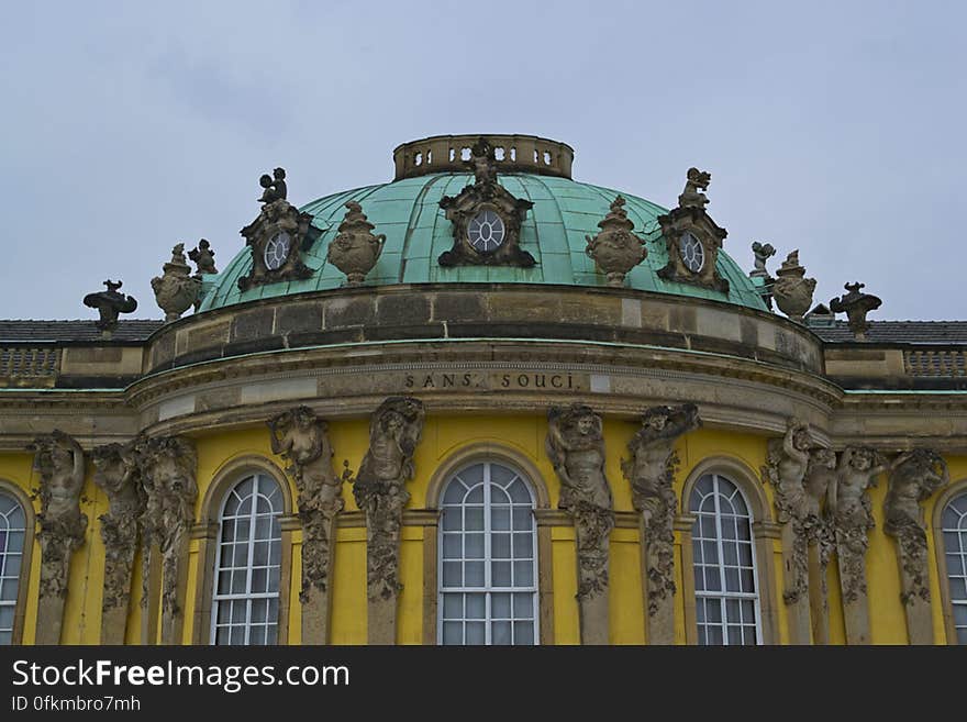 Sanssouci Rococo front with dome sustained by Atlas and Caryatids pairs, cherubs on roof and the name of the palace in gilded letters. Sanssouci Rococo front with dome sustained by Atlas and Caryatids pairs, cherubs on roof and the name of the palace in gilded letters.