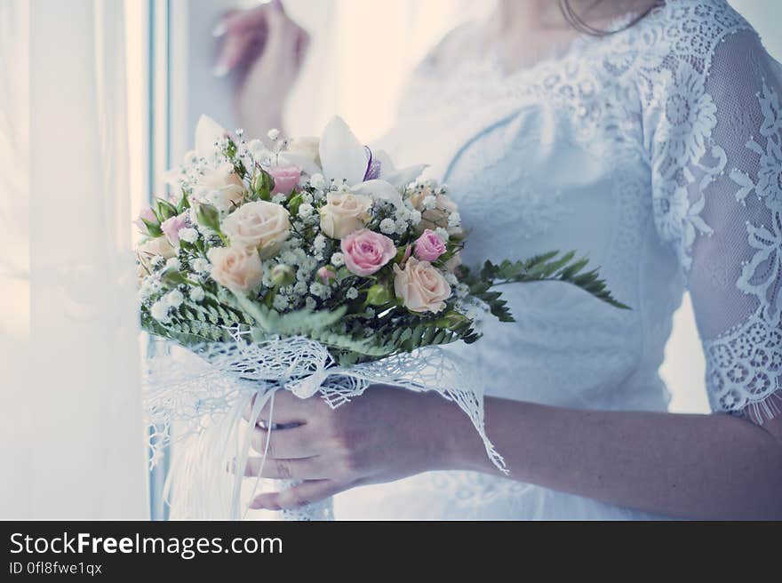 Close up of bride in white gown holding floral bouquet. Close up of bride in white gown holding floral bouquet.