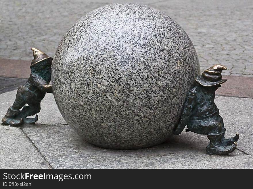 A sculpture of pair of gnomes rolling a stone. A sculpture of pair of gnomes rolling a stone.