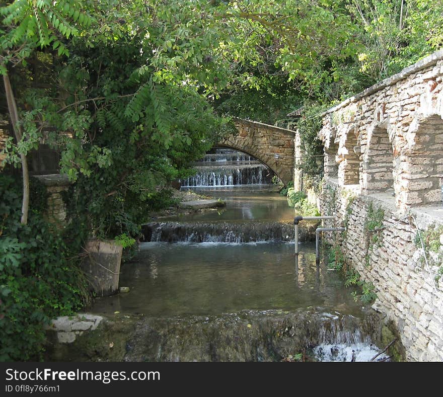 A cascading canal with riffles and a stone construction on the right bank.