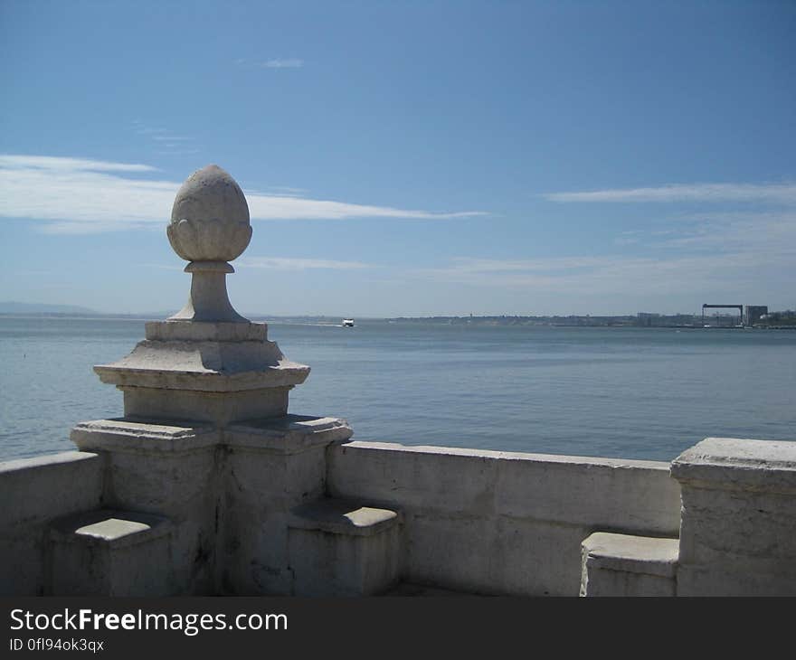 A stone sculpture on a banister overlooking the sea. A stone sculpture on a banister overlooking the sea.