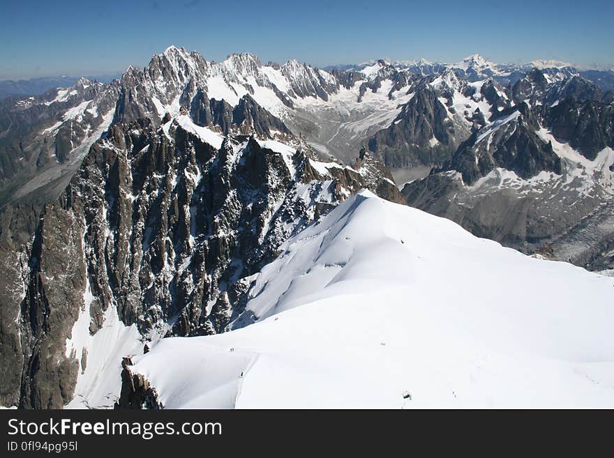 Snow covered peaks in mountain range against blue skies on sunny day. Snow covered peaks in mountain range against blue skies on sunny day.