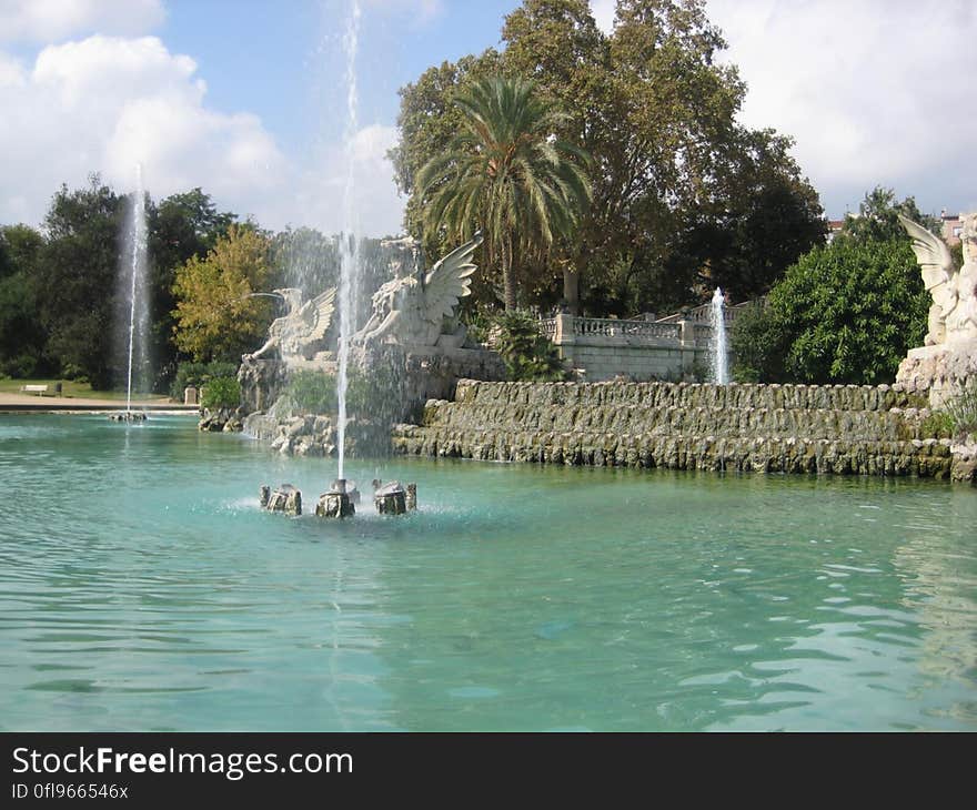 A view of a park with a large pool of water and fountain. A view of a park with a large pool of water and fountain.