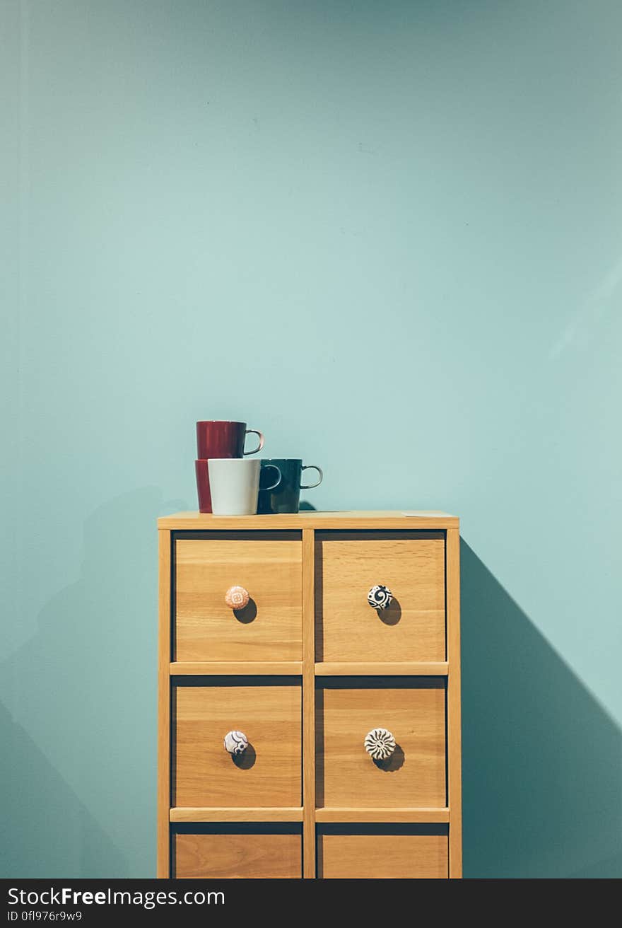 Simple wooden cabinet with mugs on top.