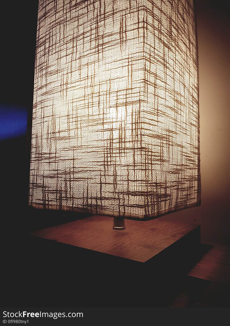 A close up of a modern lamp on a wooden table.