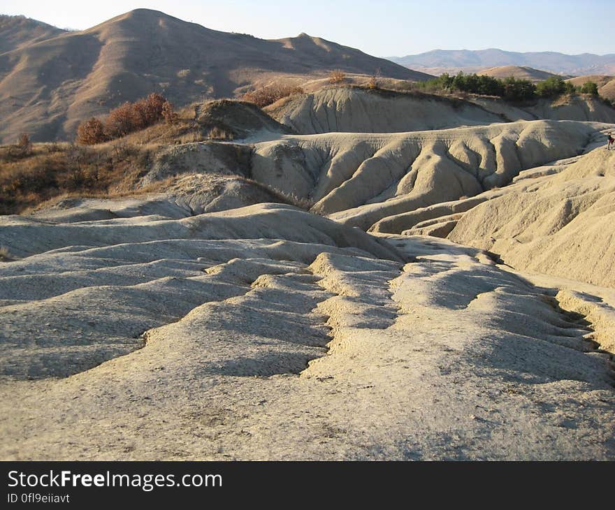 Sand dunes, hills and distant mountains in an arid climate with just a few trees surviving in the harsh conditions. Sand dunes, hills and distant mountains in an arid climate with just a few trees surviving in the harsh conditions.