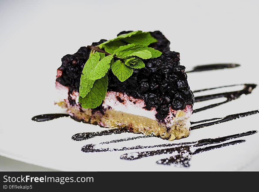 Slice of blackberry cheesecake with drizzle effect on white background.