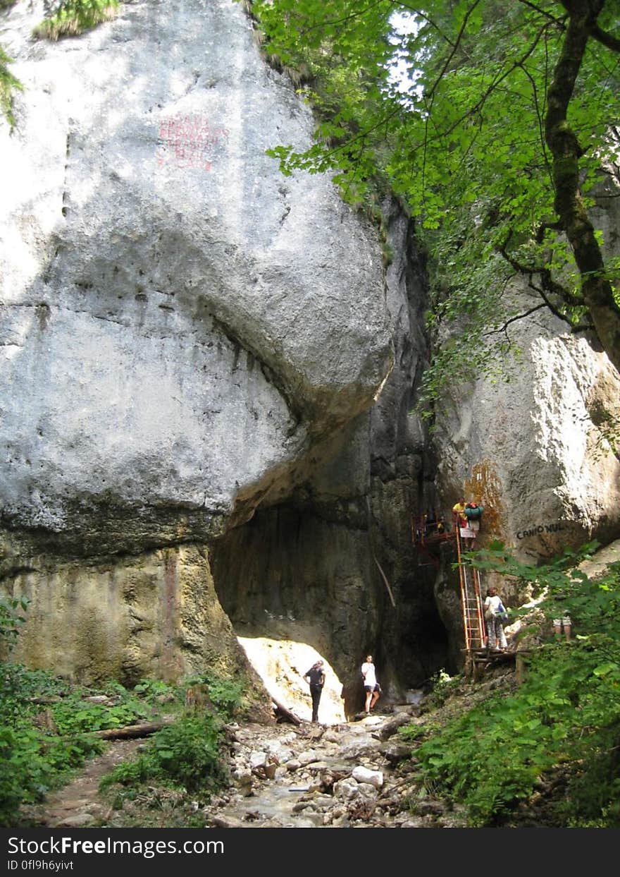 Group of explorers stood next to ladder at entrance to cave in mountains. Group of explorers stood next to ladder at entrance to cave in mountains.