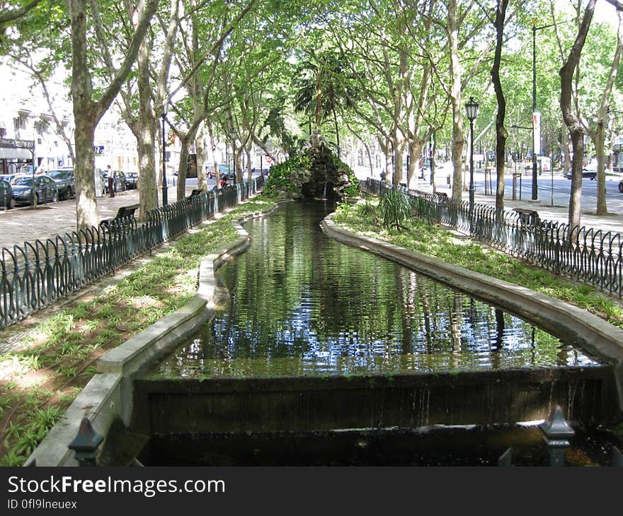 A canal flowing through a fenced park in a city. A canal flowing through a fenced park in a city.