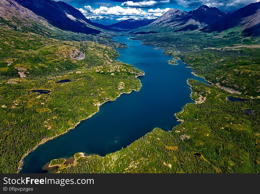 Aerial view of blue lake in green valley with mountains in background. Aerial view of blue lake in green valley with mountains in background.