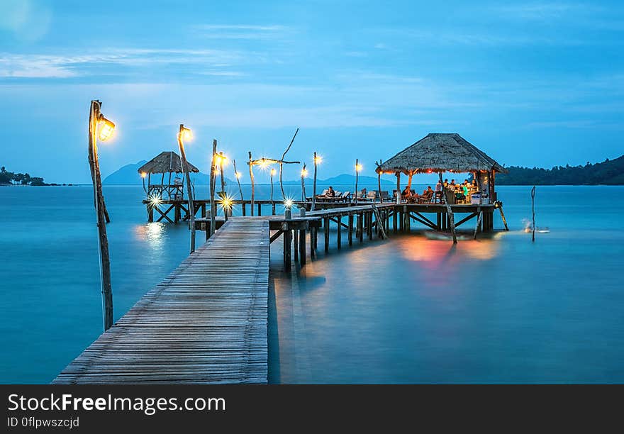 Beach bungalow at end of ocean jetty illuminated at night.