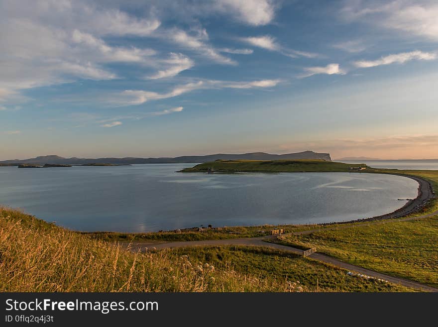 Panoramic view of curved ocean bay at dawn with cloudscape background.