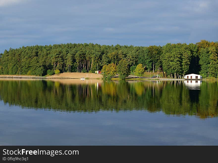 A lake with a forest and houses on the shore. A lake with a forest and houses on the shore.