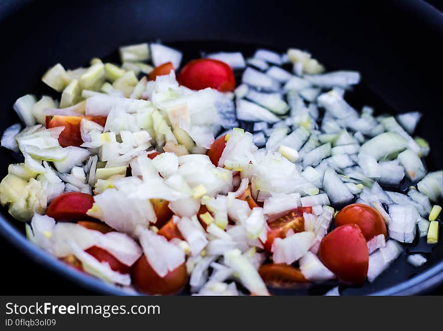 A frying pan with chopped tomatoes and onions. A frying pan with chopped tomatoes and onions.