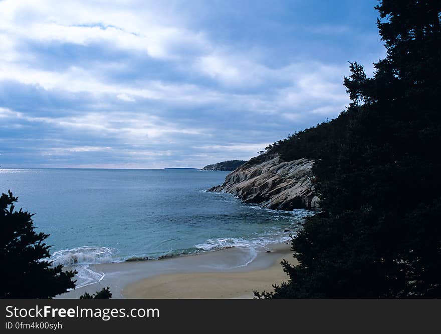 Acadia National Park — A beautiful coastal view of the waves crashing at sandy inlet surrounded by a rocky coast in Acadia National Park. Granite underlies much of Acadia which helps gives the park it&#x27;s rugged and rough character. Photo credit: John Mosesso, USGS.