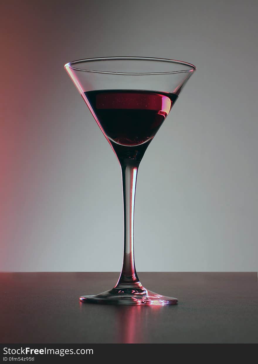 Side view of red cocktail drink in tall glass on table.