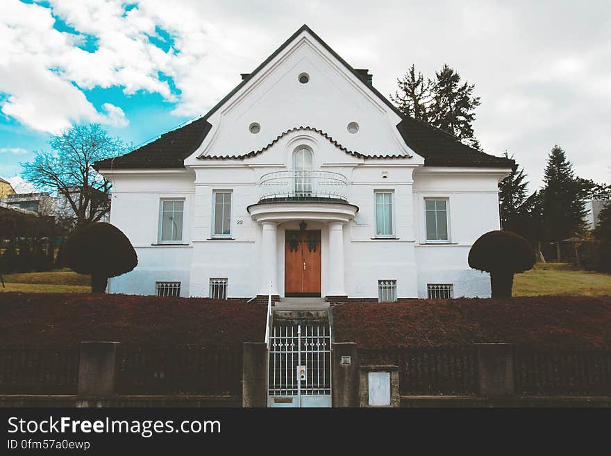 Exterior of detached modern home viewed from front with cloudscape background.