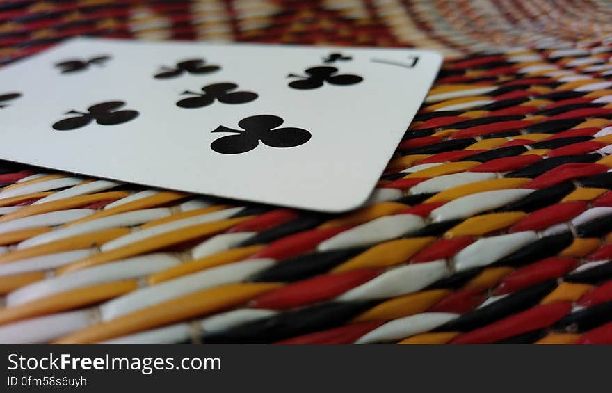 Close up of seven of clubs card on colorful plastic woven textile. Close up of seven of clubs card on colorful plastic woven textile.