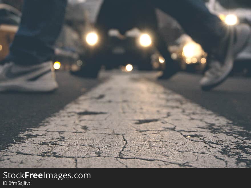 Feet of pedestrians in crosswalk on street with lights from stopped traffic. Feet of pedestrians in crosswalk on street with lights from stopped traffic.