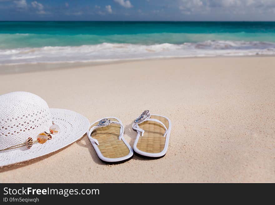 White Hat Beside White Flip Flops Near Short