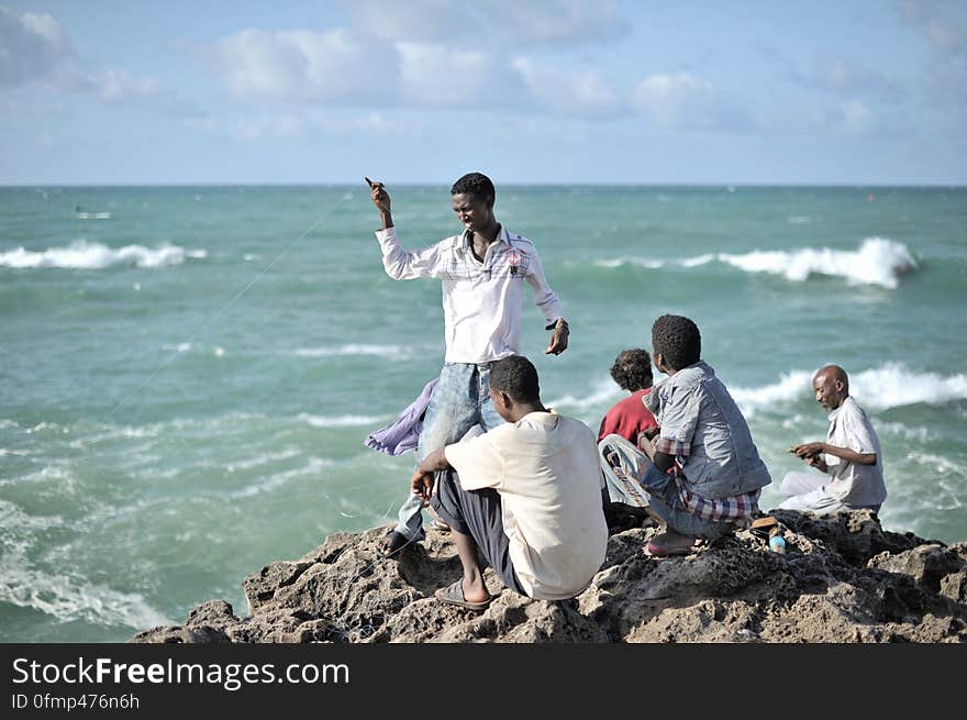 Young men sit fishing on a rocky outcrop near Mogadishu&#x27;s fish market on May 22. AU UN IST PHOTO / TOBIN JONES. Young men sit fishing on a rocky outcrop near Mogadishu&#x27;s fish market on May 22. AU UN IST PHOTO / TOBIN JONES.