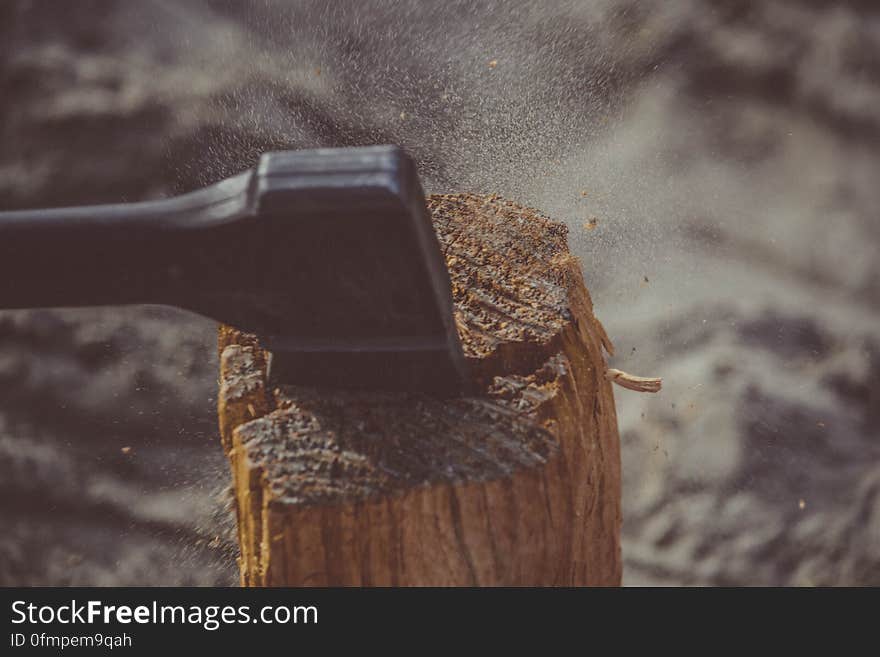 An axe or maul splitting log for firewood. An axe or maul splitting log for firewood.