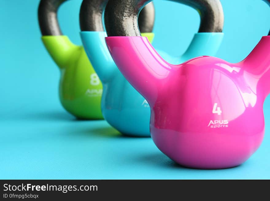 A trio of colorful kettlebells on blue background.