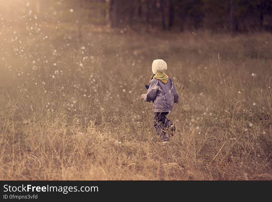 A young boy running through raindrops in a field. A young boy running through raindrops in a field.