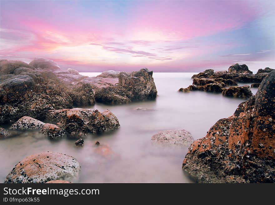 A rocky beach and colored sky at dusk. A rocky beach and colored sky at dusk.