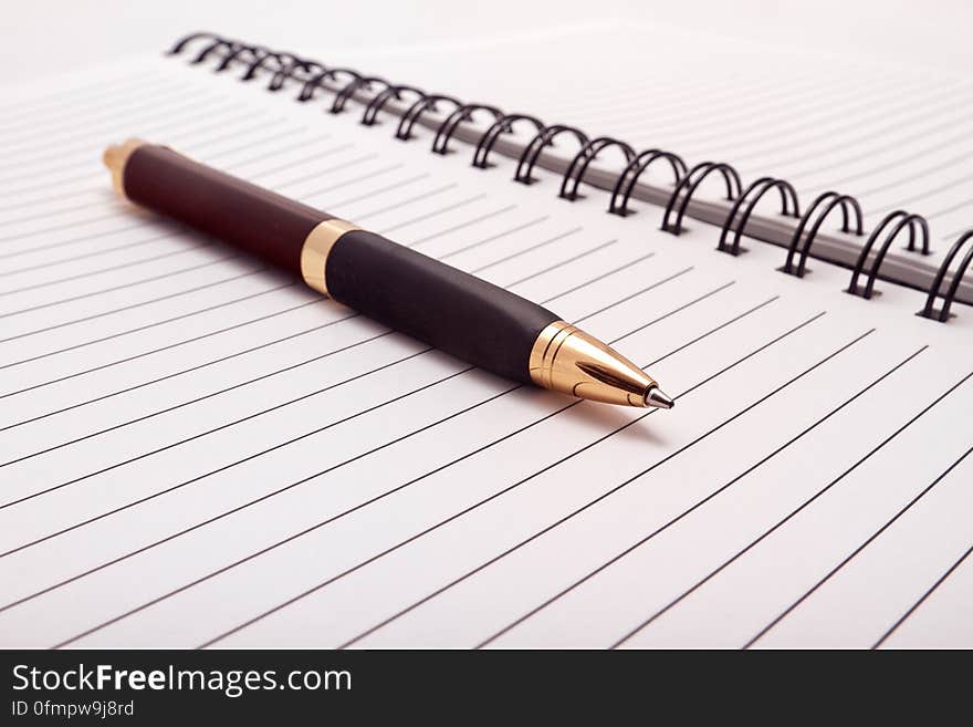 A close up of an elegant pen on an open notebook. A close up of an elegant pen on an open notebook.