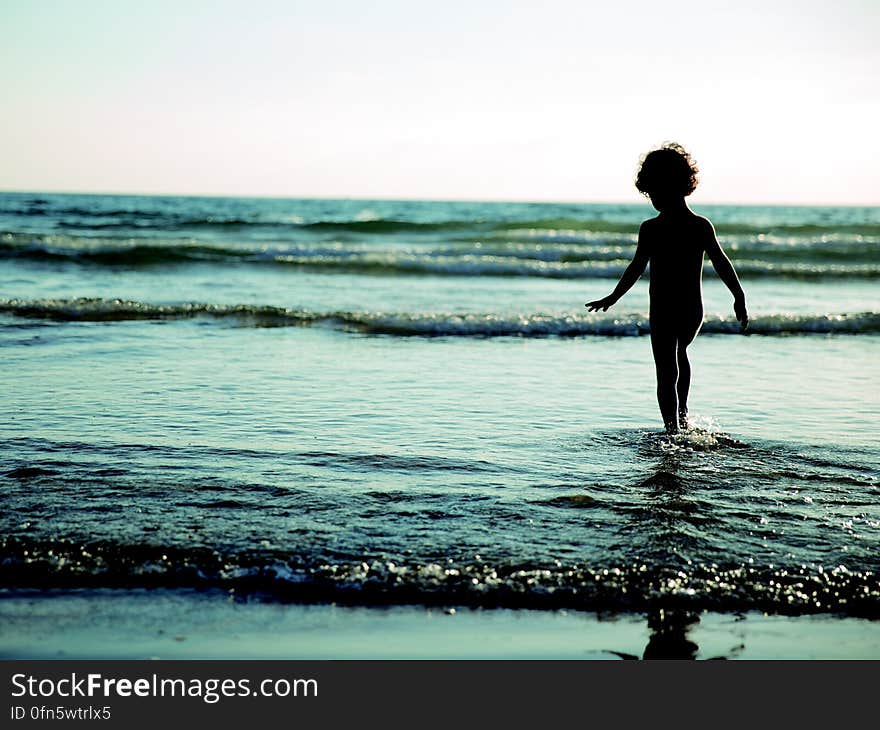 Child Walking on Seashore during Daytime