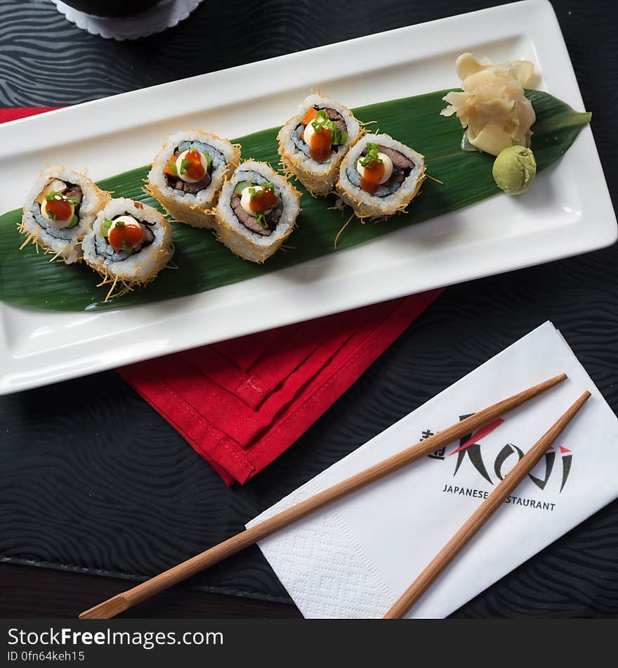 Overhead of sushi pieces on banana leaf on white china serving dish with fresh ginger and wasabi. Overhead of sushi pieces on banana leaf on white china serving dish with fresh ginger and wasabi.