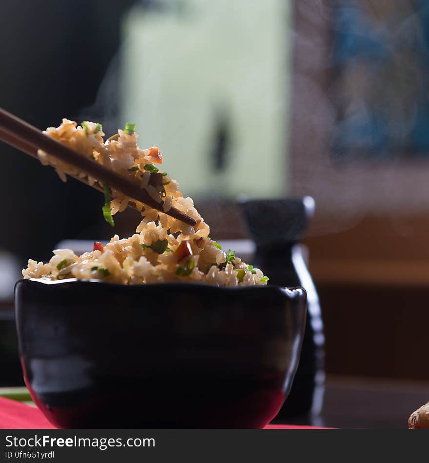 Close up of bowl with fried rice with chopsticks above in restaurant. Close up of bowl with fried rice with chopsticks above in restaurant.