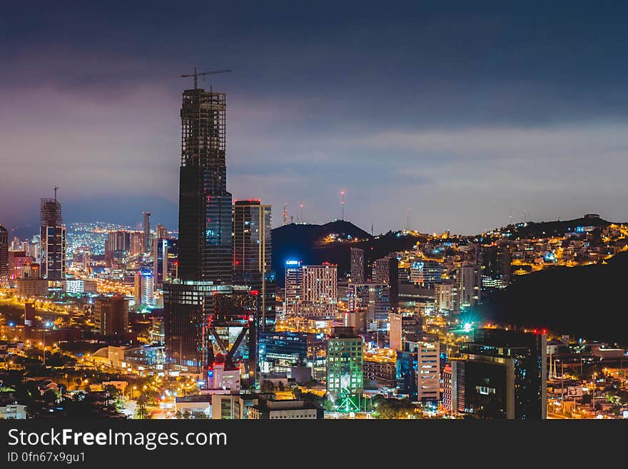 A modern city at night with a tall skyscraper being built.