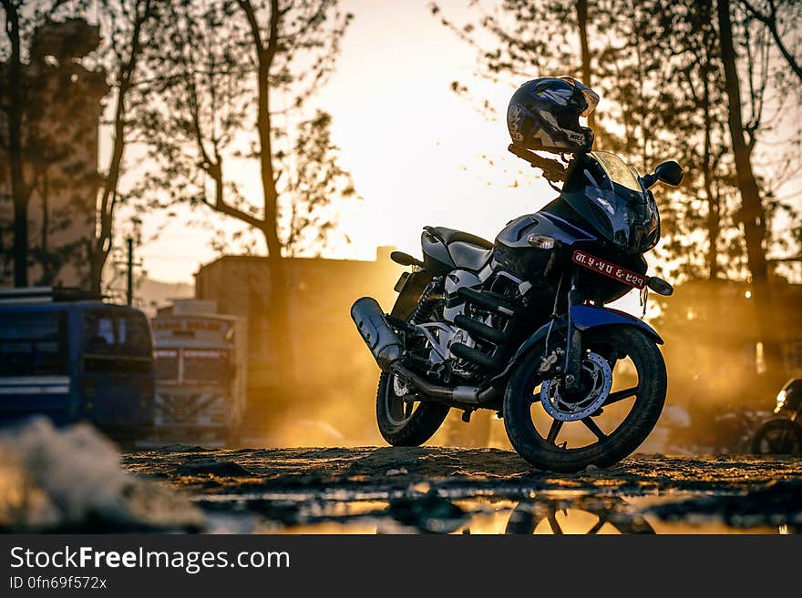 Powerful motorbike parked off the road with a safety helmet on the handlebars lit by a gold light at sunset. Powerful motorbike parked off the road with a safety helmet on the handlebars lit by a gold light at sunset.