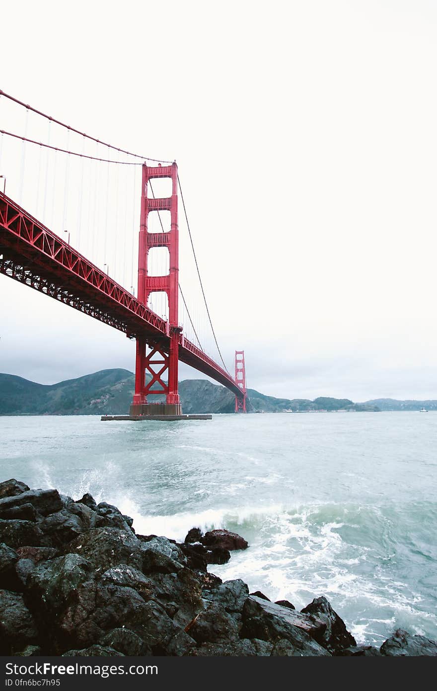 The Golden Gate Bridge and sea waves splashing against the rocky shore, San Francisco, California.