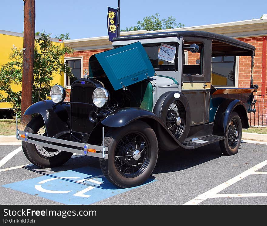 Vintage auto parked in handicapped parking space outside brick building on sunny day. Vintage auto parked in handicapped parking space outside brick building on sunny day.