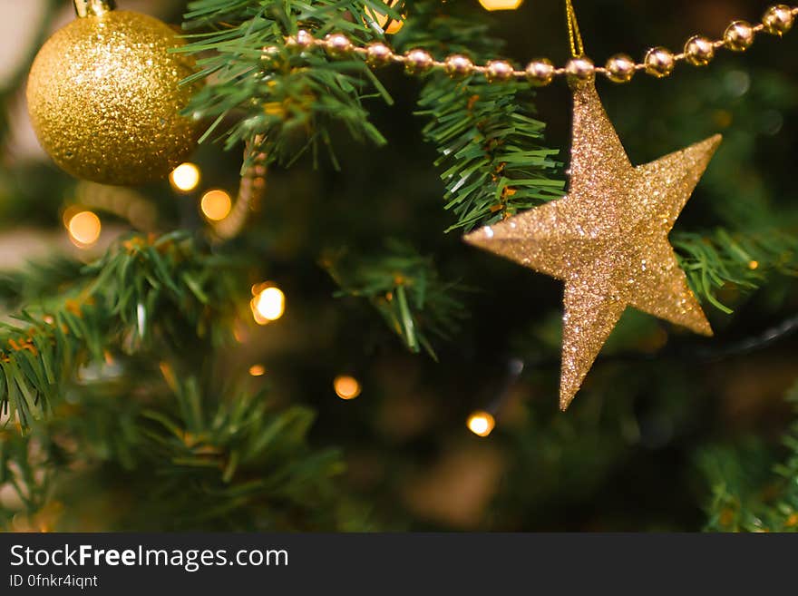 Close up of gold garland, star and ball ornaments on Christmas tree with lights. Close up of gold garland, star and ball ornaments on Christmas tree with lights.