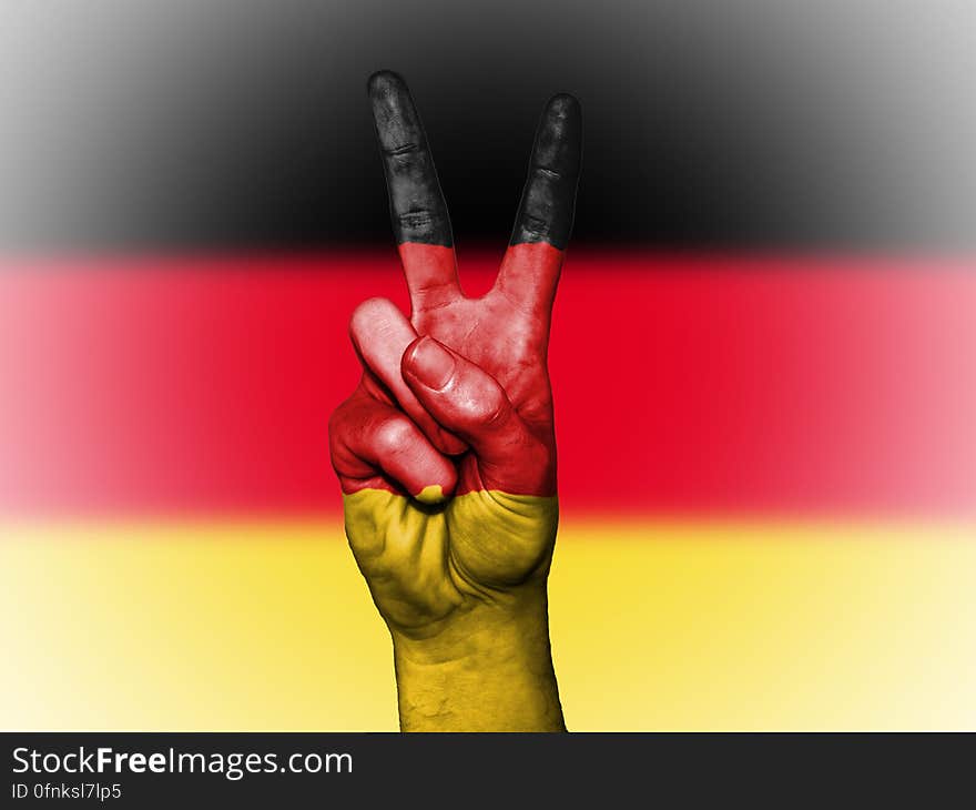 A person doing the V sign with fingers in front of the German Flag. A person doing the V sign with fingers in front of the German Flag.