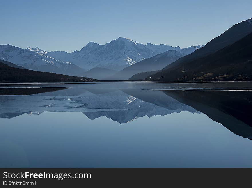 A clear lake with mountains reflecting from the surface. A clear lake with mountains reflecting from the surface.