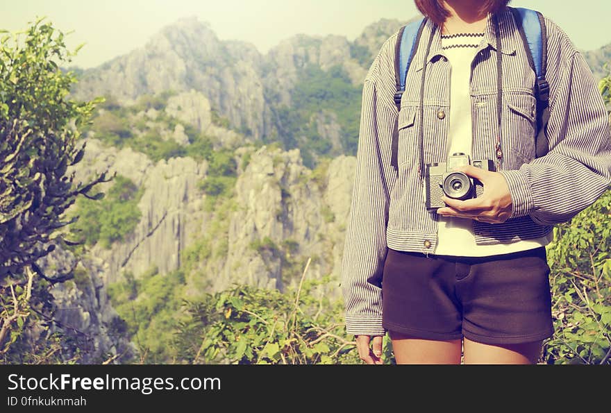 A traveler with a camera standing in front of a mountain landscape. A traveler with a camera standing in front of a mountain landscape.