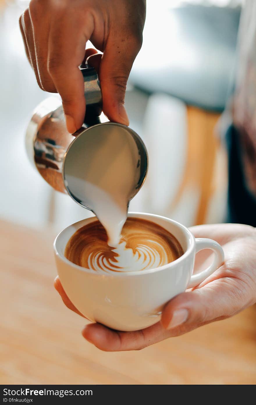 A barista pouring milk foam in a cup of coffee to make latte art. A barista pouring milk foam in a cup of coffee to make latte art.