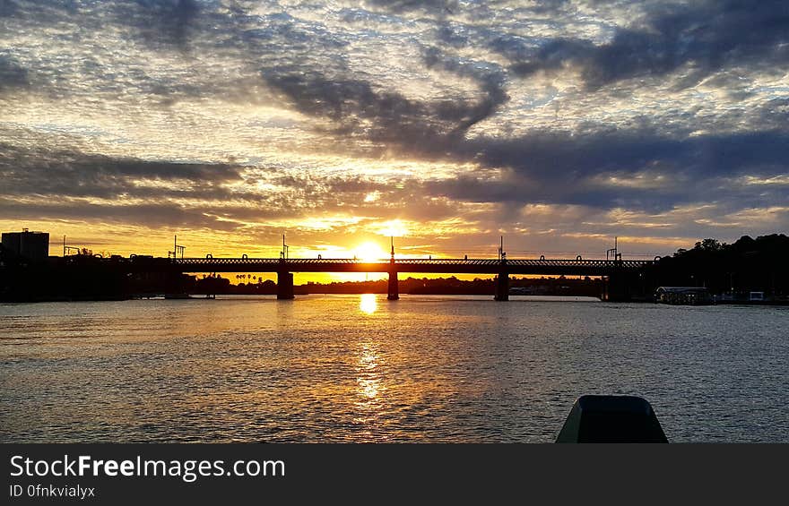 A silhouetted bridge at sunset and sunlight reflecting on the water surface.