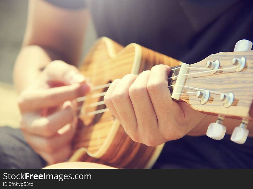 A close up of a man playing ukulele.