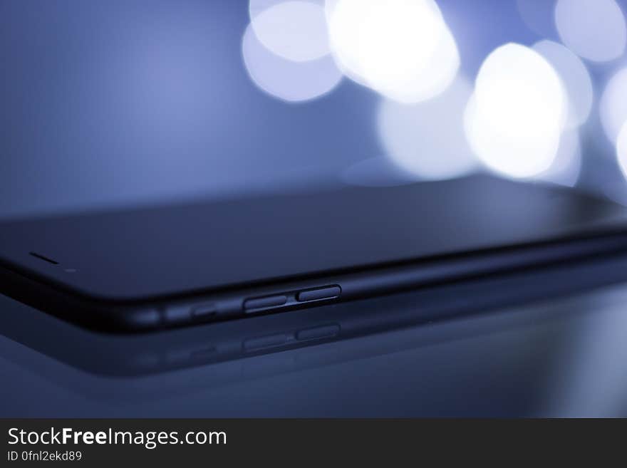 Profile of black smartphone with bokeh light background. Profile of black smartphone with bokeh light background.