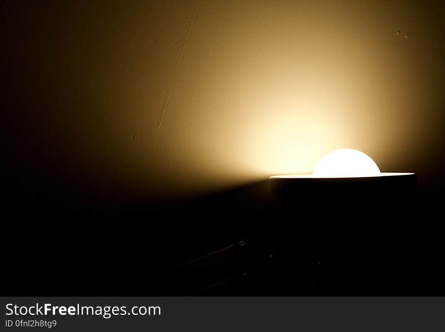 Light bulb illuminating shade against orange wall with copy space. Light bulb illuminating shade against orange wall with copy space.